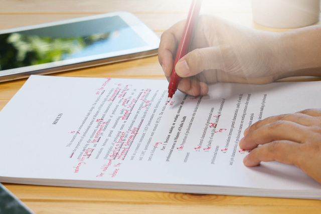 person self-edits manuscript with red pen